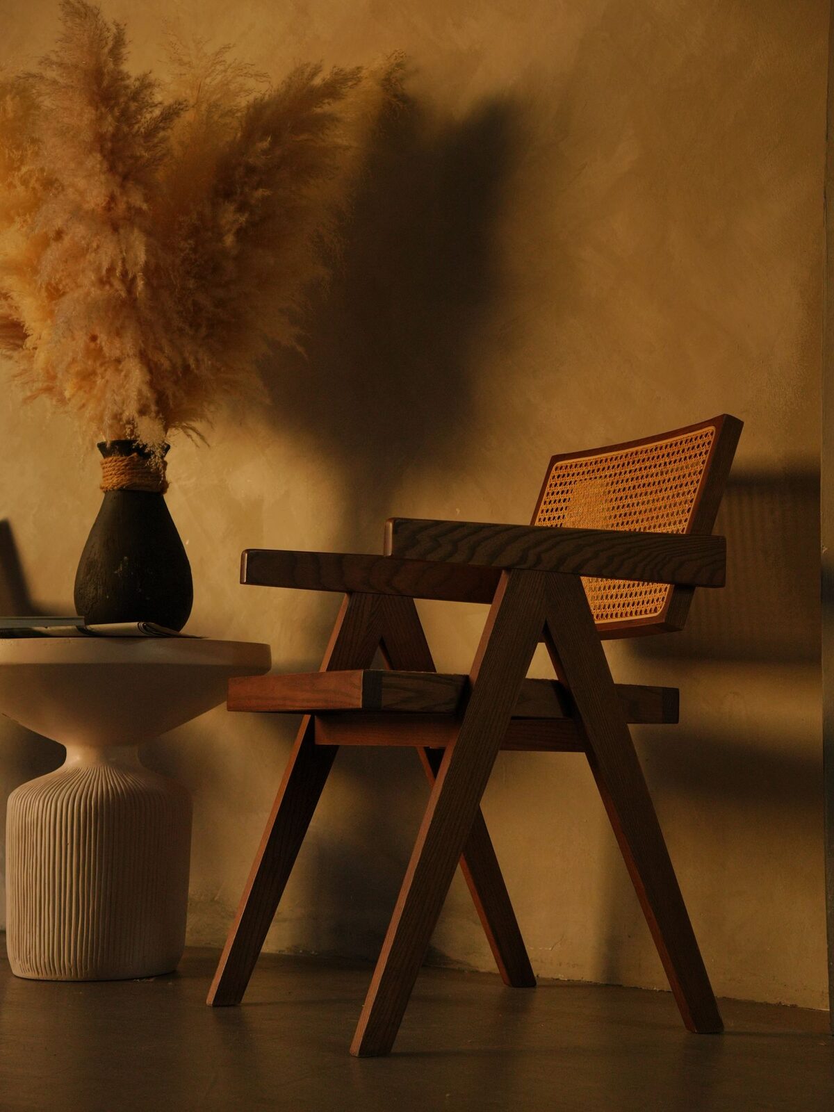 Reading corner with a rattan chair and pampas grass beside a bright window